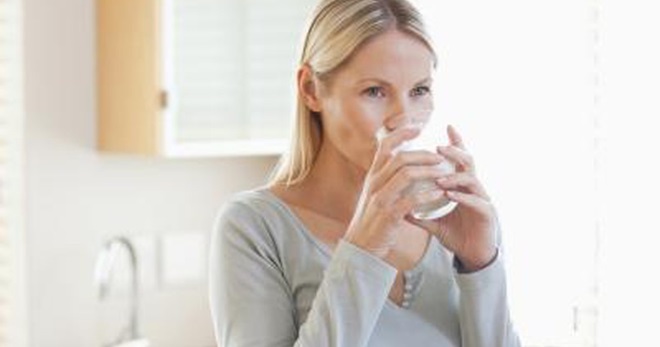 Женщина пьет стакан с водой